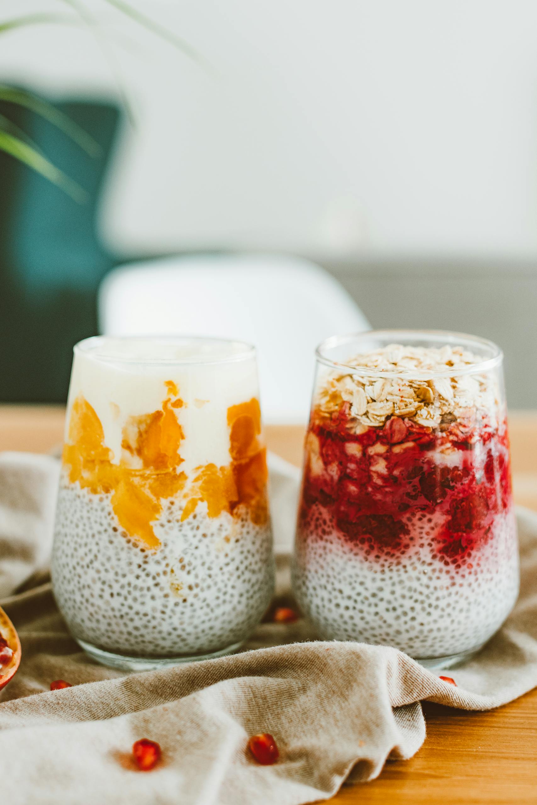 Close-up of chia pudding topped with mixed fruits and granola in glass jars.